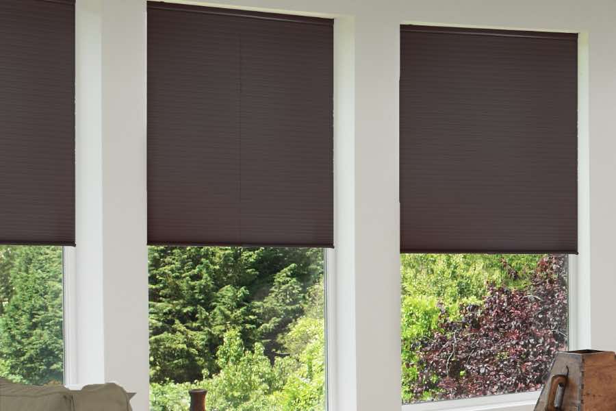 Dark cellular shades cover large windows in living room